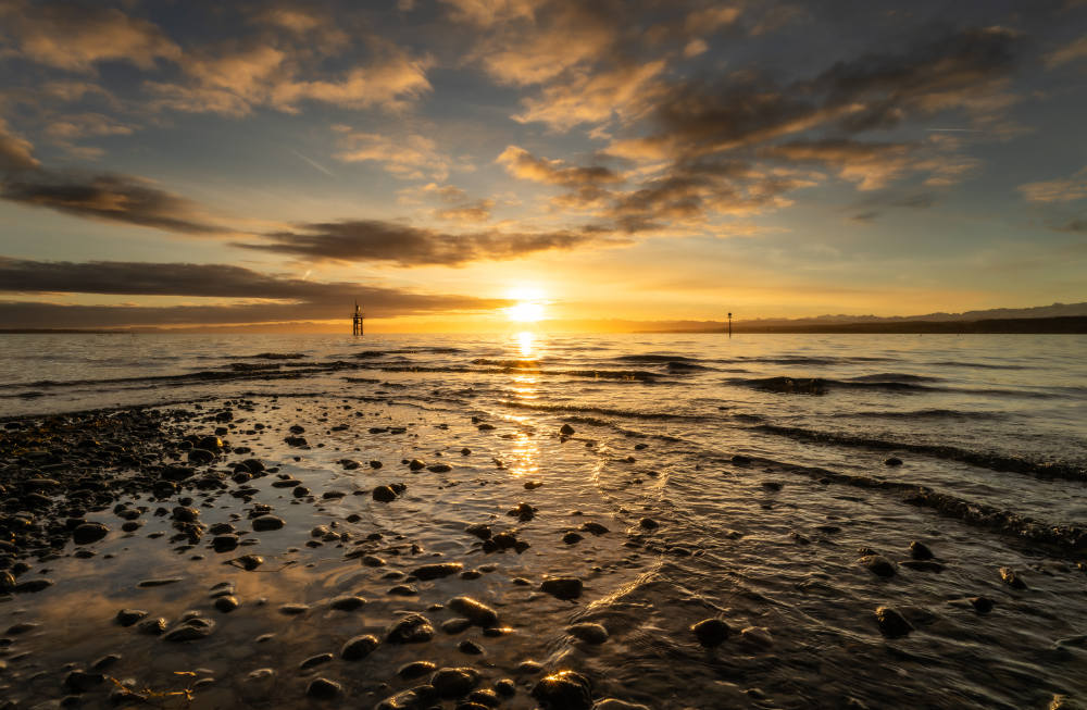 Sonnenaufgang am Bodensee mit Steinen im Wasser